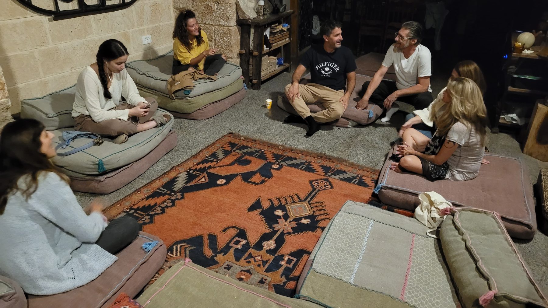 מפגש קבוצתי אינטימי, יושבים על כריות סביב שטיח